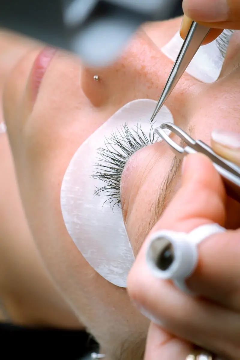 woman getting professional lash extensions done by lash technician