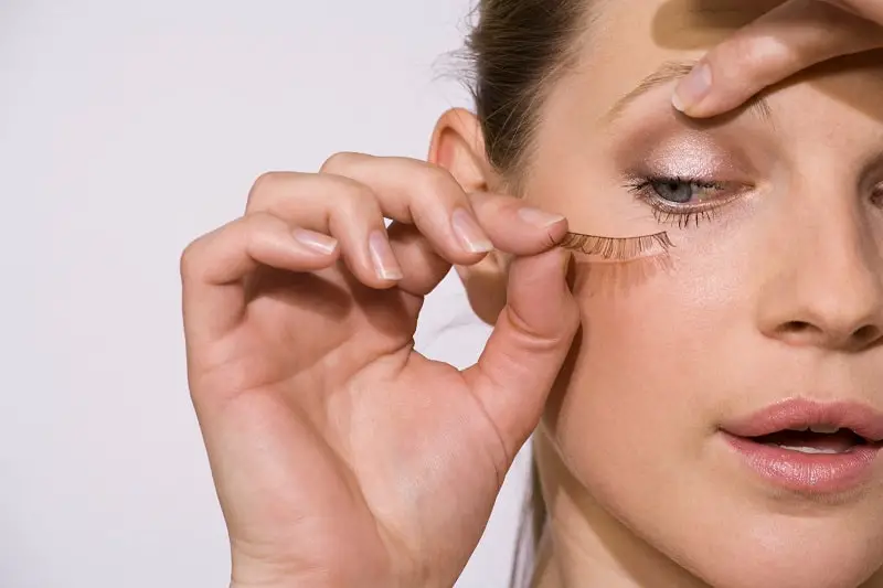 woman applying false eyelashes