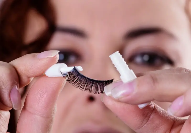 woman puts eyelash glue onto a fake eyelash