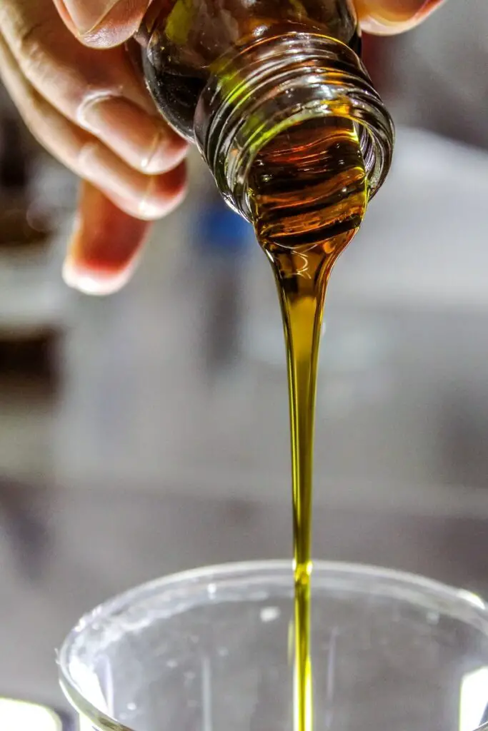 close-up of a stream of golden liquid organic honey pouring from a bottle