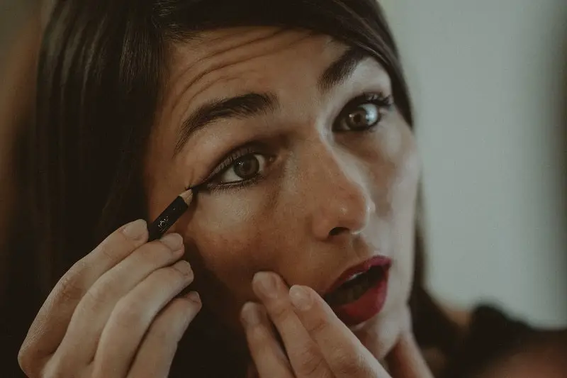 woman applying black eyeliner pencil to her eyelid