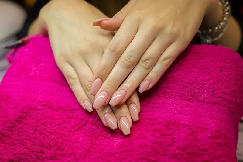 close-up of a woman's polygel nails on a pink towel in a nail salon