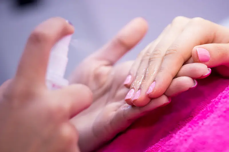 close-up of a woman's hand on pink towel in a nail salon getting polygel slip solution applied to her nails