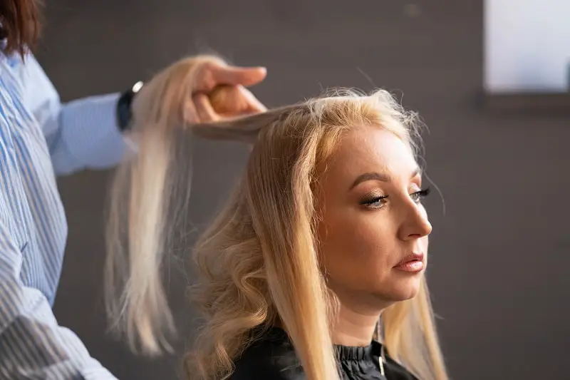 woman perms bleached hair in a beauty salon