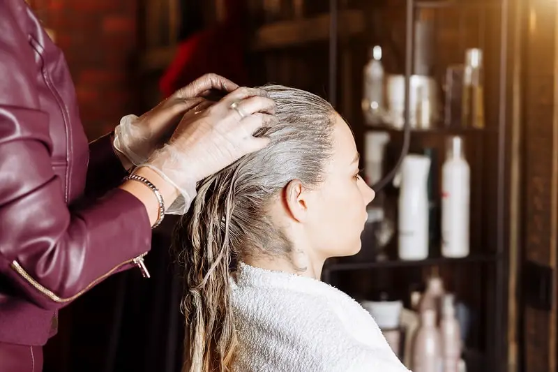 hairstylist straightens woman's permed hair at a beauty salon
