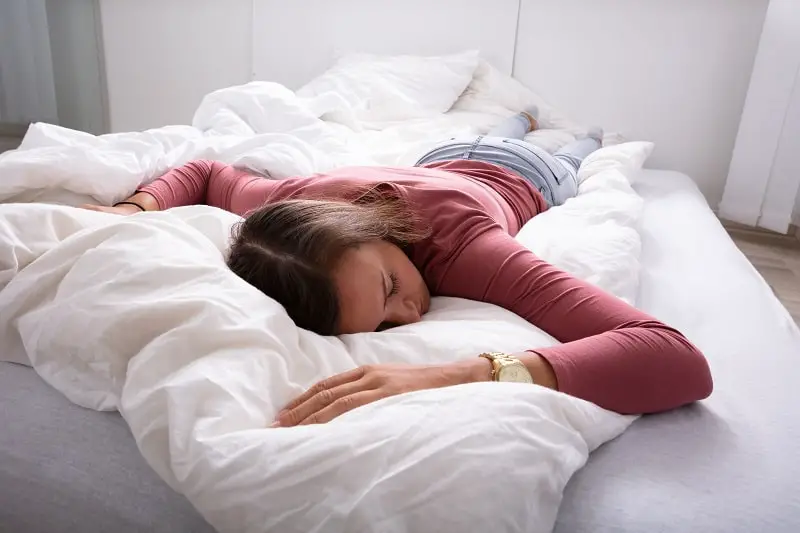 young woman wearing mascara lying in bed sleeping
