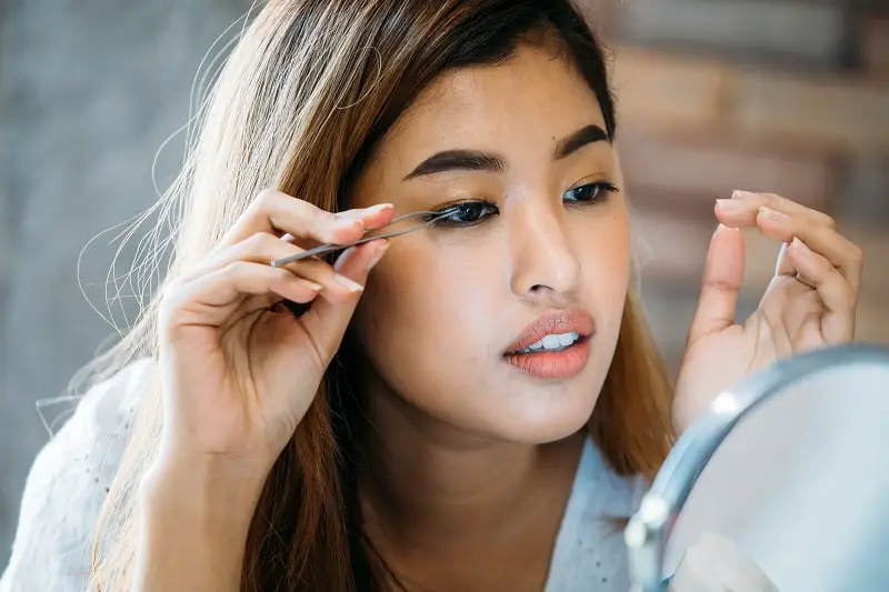 pregnant Asian woman applying fake lashes using Duo eyelash glue